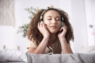 Yatakta müzik dinleyen genç kadın 