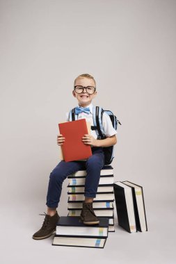 Kitap yığını arasında gülümseyen çocuk portresi 