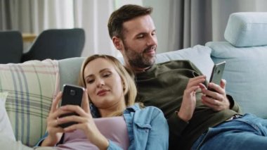 Telefon kullanıp kanepede uzanan olgun bir çift.