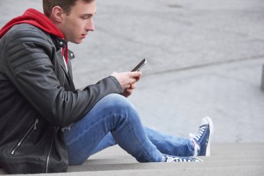 Genç adamın akıllı telefonunu kullanışının yan görüntüsü 