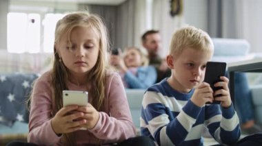 Oturma odasında cep telefonu kullanan çocuklar