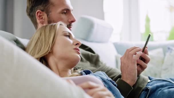 携帯電話を使って寝そべってる夫婦 — ストック動画
