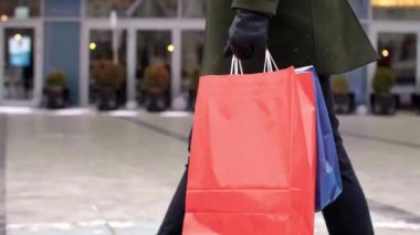 Alışveriş torbalarıyla sokakta yürüyen bir adamın alt tabakası.