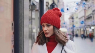 Giysileriyle dükkanın vitrinine bakan genç kadın.