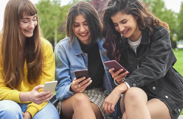 Três Mulheres Bonitas Olhando Para Telefones Inteligentes — Fotografia de Stock