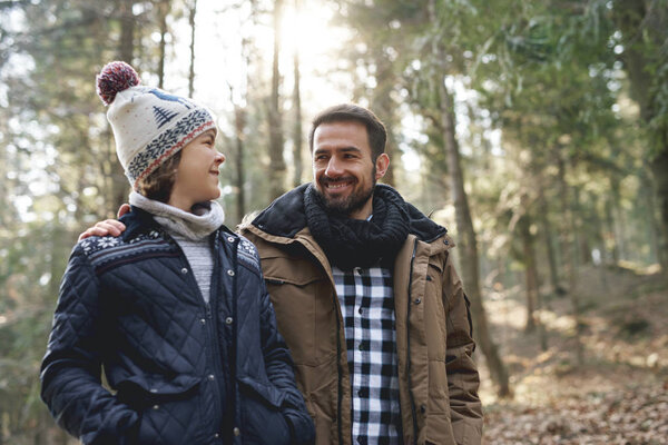 Счастливый отец и сын-подросток, гуляющие по осеннему лесу
