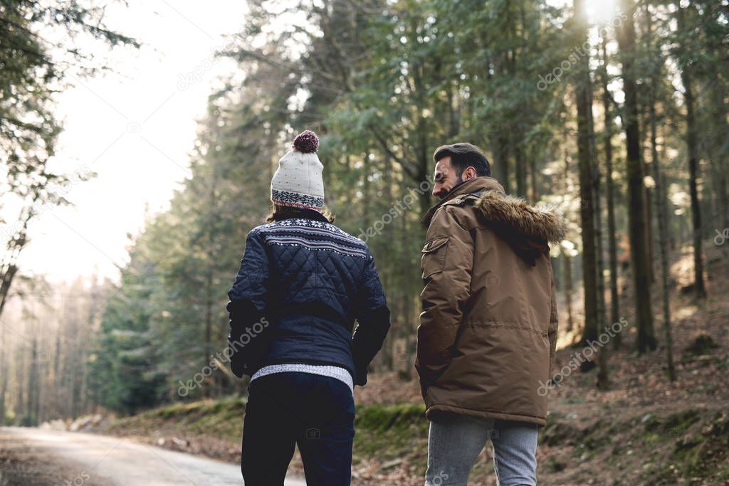 Rear view of father and son walking in autumn forest 