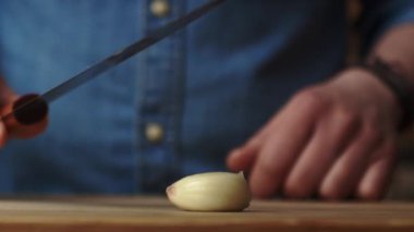 Sarımsağı mutfak bıçağıyla ezmenin statik videosu. 8K 'da kırmızı helyum kamerayla çekildi.