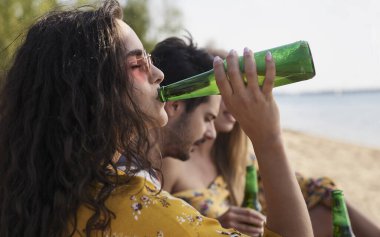 Plajda arkadaşlarıyla bira içen bir kıza yakın durun.. 