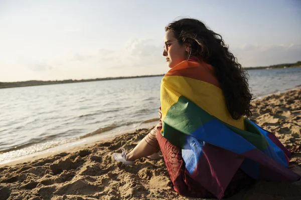 Ragazza Seduta Sulla Spiaggia Guardando Tramonto Con Bandiera Arcobaleno — Foto Stock