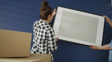 Duvara resim çerçevesi asan bir çiftin videosu. 8K 'da kırmızı helyum kamerayla çekildi.