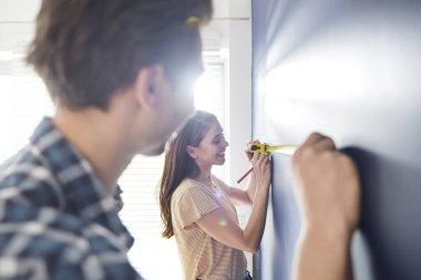 İşbirliği yapan çift duvardaki mezurayı kullanıyor.