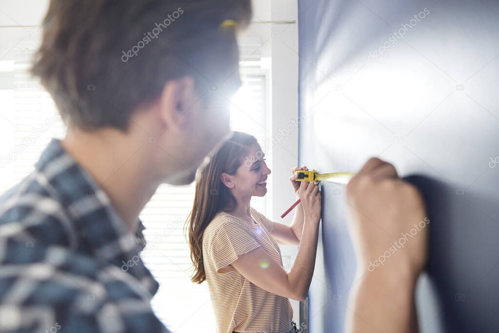 Cooperating couple using measure tape on the wall
