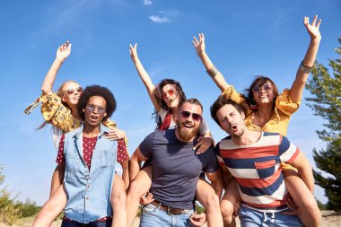 Genç erkekler kız arkadaşlarını sırtında taşıyor. 