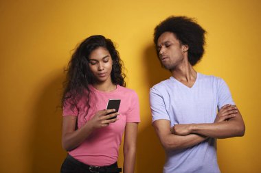 Kıskanç adam kız arkadaşının telefonuna bakıyor.