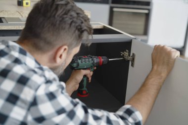 Mutfak mobilyalarına menteşe takan adam            