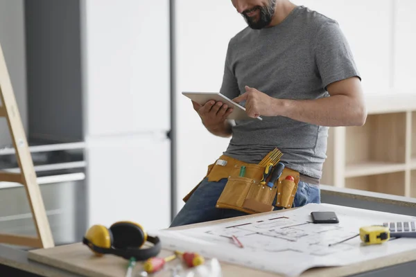 Lachende Timmerman Kijkt Naar Iets Een Tablet — Stockfoto