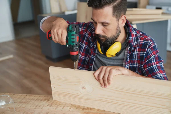 Konzentrierter Tischler Bohrt Eine Holzplanke — Stockfoto