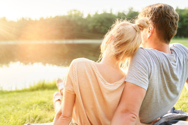 Couple in love watching sunset by the lake