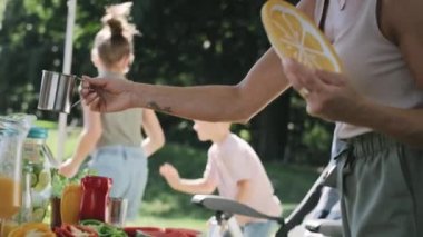 Çocuklar oynarken ebeveynlerin meyve suyunu içtiği video. 8K 'da kırmızı helyum kamerayla çekildi..