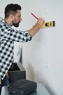  Marangozun duvardaki ruh seviyesini kullanışının yan görüntüsü                              