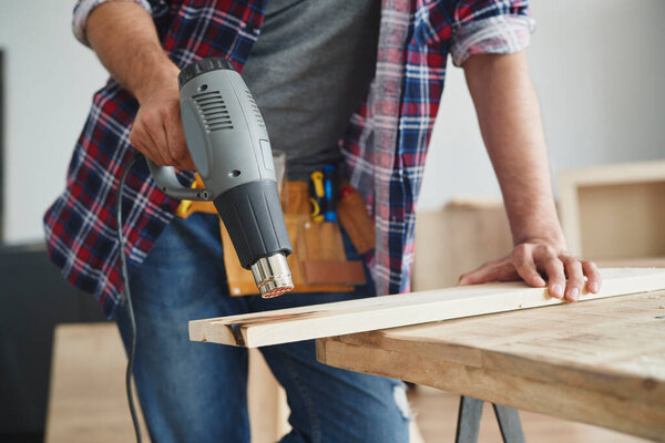 Carpenter using wood heat gun                               
