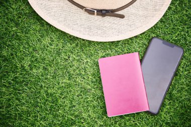 Yeşil çimenlikteki telefon şapkası ve pasaport manzarası