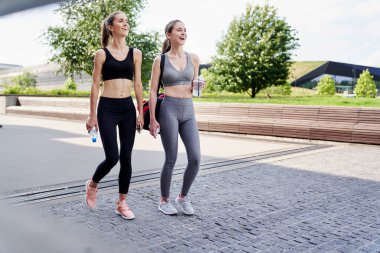 İki atletik gülümseyen kadın antrenmana gidiyor.                               