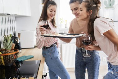 Üç arkadaş taze pişmiş pizza kokusunun tadını çıkarıyor.                               