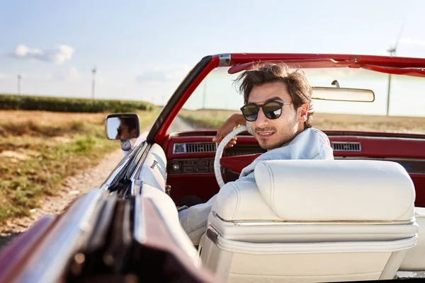 Üstü açık kırmızı arabalı yakışıklı bir adam.                               