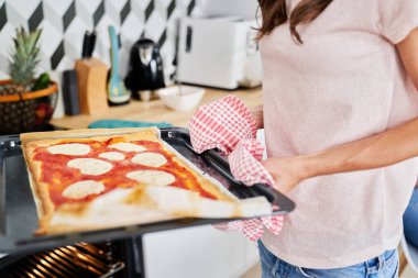 Ev yapımı pizzayı fırından çıkar.                               