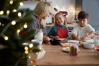 Anne ve çocuklar Noel kurabiyesi yapıyorlar.