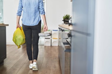 Ayrımcı kağıtları ve plastikleri atmak üzere olan bir kadın.