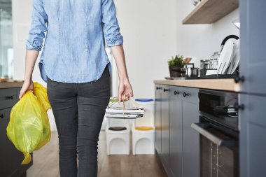 Kadın ayrıştırılmış kağıt ve plastikle çöpe gidiyor.