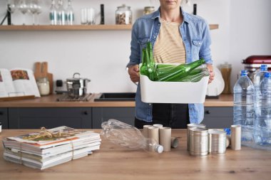 Cam şişelerle dolu bir kutu taşıyan kadın.