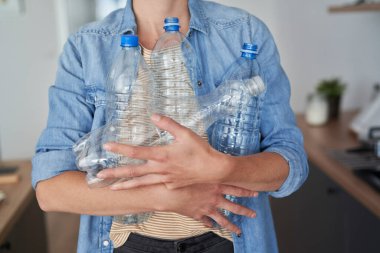 Geri dönüşüm için bir sürü boş plastik şişe taşıyan kadın.