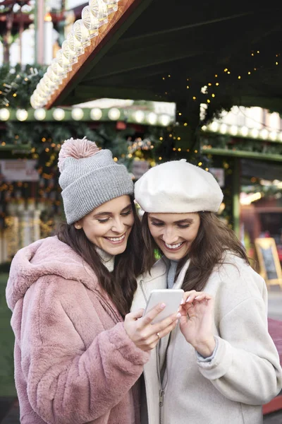 Két Barát Mobilt Böngészve Karácsonyi Piacon — Stock Fotó