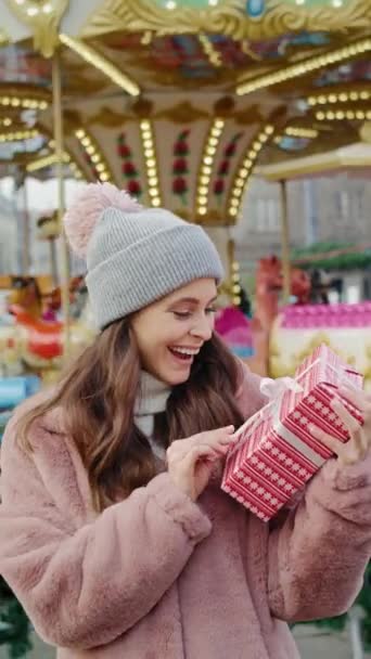 クリスマスプレゼントとカルーセルを背景にした女性のビデオ 8Kでレッドヘリウムカメラで撮影 — ストック動画