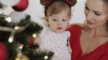 Anne ve bebeğinin Noel ağacının yanında videosu. 8K 'da kırmızı helyum kamerayla çekildi..