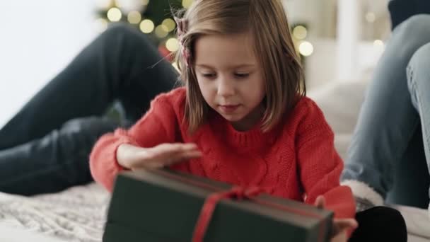 Video of child opening gift and parents in the background. Shot with RED helium camera in 8K. — Stock Footage Video Child Opening Gift Parents Background Shot Red Helium Camera Royalty Free Stock Footage