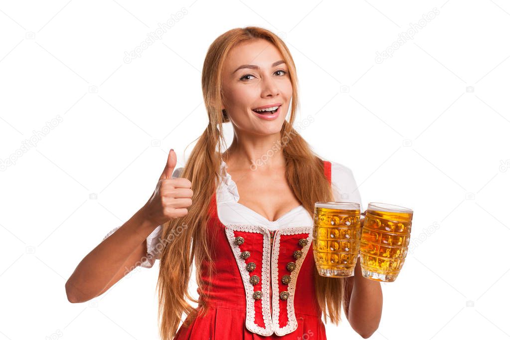 Beautiful happy Bavarian waitress smiling cheerfully to the camera showing thumbs up while holding two mugs of delicious beer isolated on white, copy space on the side. Oktoberfest, drinking, party