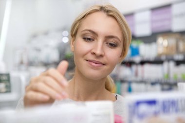 Sevinçle, eczanede alışveriş yaparken gülümseyerek mutlu bir güzel kadının kapatın. Büyüleyici kadın müşteri Medikal eczane satış incelenmesi. Sigorta, tıbbi bakım kavramı