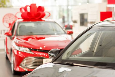 Bayilik salon, kopya alanı Satılık Yeni arabalar. Güzel parlak kırmızı modern sedan çatıda büyük bir yay ile. Hediyelik araba showroom, mevcut. Yeni araba konsepti satın alma. Kazanan araba reklam