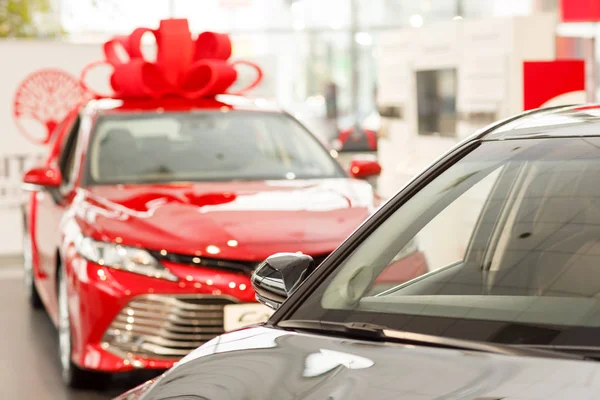 Bayilik salon, kopya alanı Satılık Yeni arabalar. Güzel parlak kırmızı modern sedan çatıda büyük bir yay ile. Hediyelik araba showroom, mevcut. Yeni araba konsepti satın alma. Kazanan araba reklam