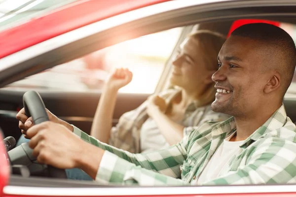 幸福的夫妇一起乘车旅行 英俊的非洲男人微笑着高兴 而驾驶他的车与他欢快美丽的女友在乘客座位上 年轻人和他的女朋友在车里 — 图库照片