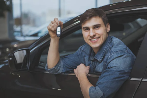 Jovem Animado Sorrindo Segurando Chaves Carro Sentado Novo Automóvel Concessionária — Fotografia de Stock