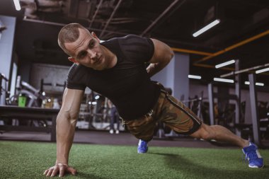 Tam uzunlukta bir kadeh yakışıklı kaslı erkek atlet puchups tek elle yapıyor. Bir kol şınav sağlıklı güçlü fitness adam spor stüdyoda çalışma dışarı. Motivasyon kavramı