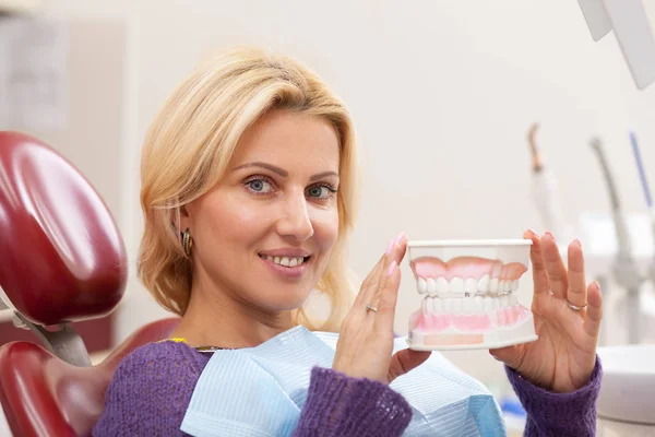 健康的な白い歯クリニックで歯科の椅子に座って 嬉しそう笑ってと 美しい幸せな熟女 プロの歯科医師による口腔内診査を待っている歯の型を保持している魅力的な女性 — ストック写真