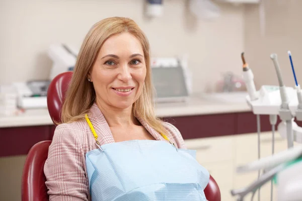 坐在诊所牙科椅上的老太太 等待与牙医的医疗预约 愉快的中年妇女在牙科诊所对着镜头微笑 植入物 假牙概念 — 图库照片