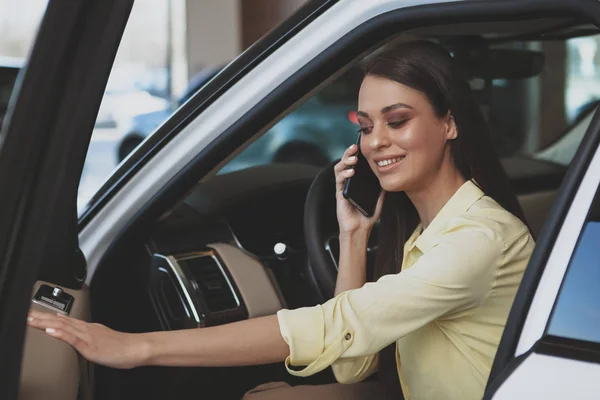 Donna attraente utilizzando il suo smartphone mentre bying nuova auto — Foto Stock